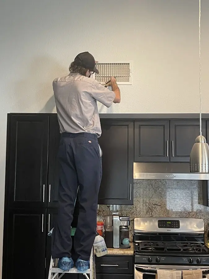 Technician inspecting an air vent during HVAC service in Lakehills